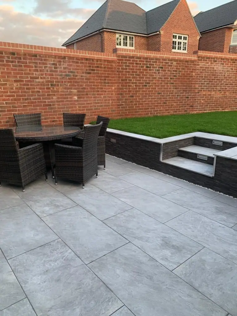 Finished porcelain patio with garden furniture and raised lawn