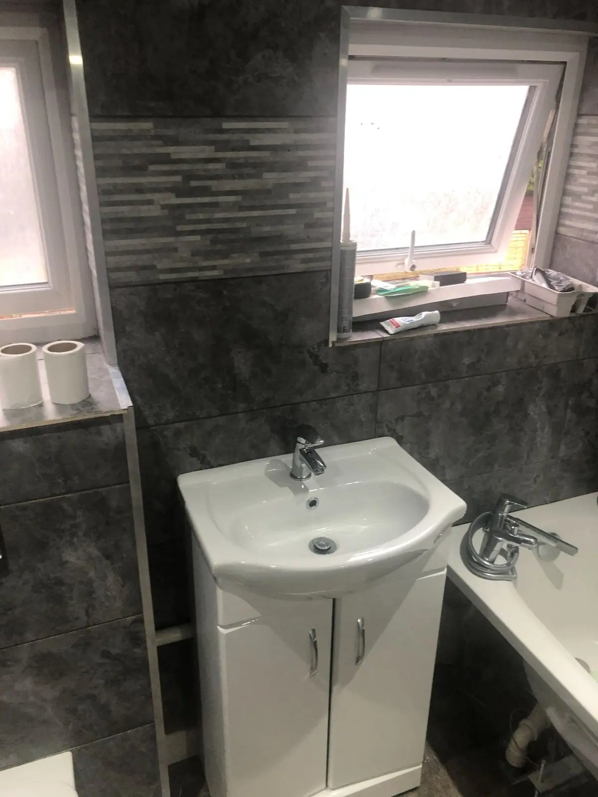 Vanity basin under the window with grey wall tiles