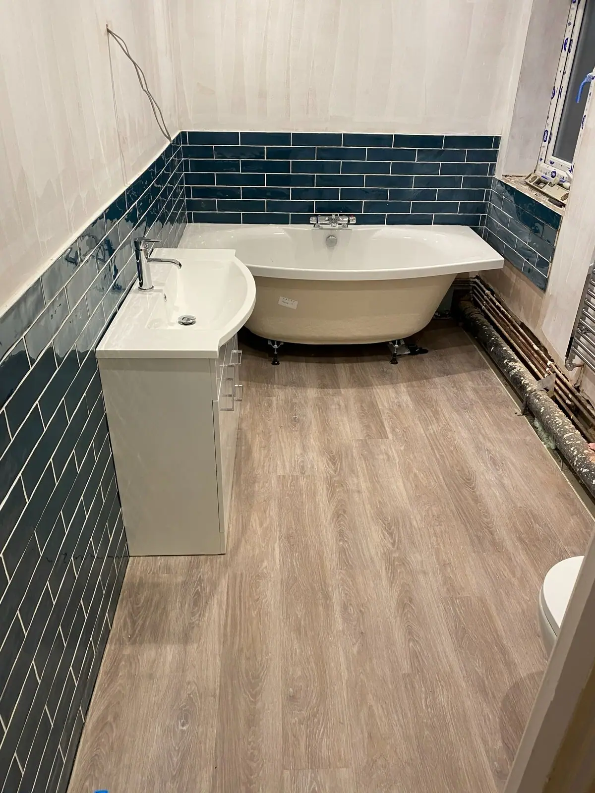 Bathroom with teal metro tiles and a freestanding bath