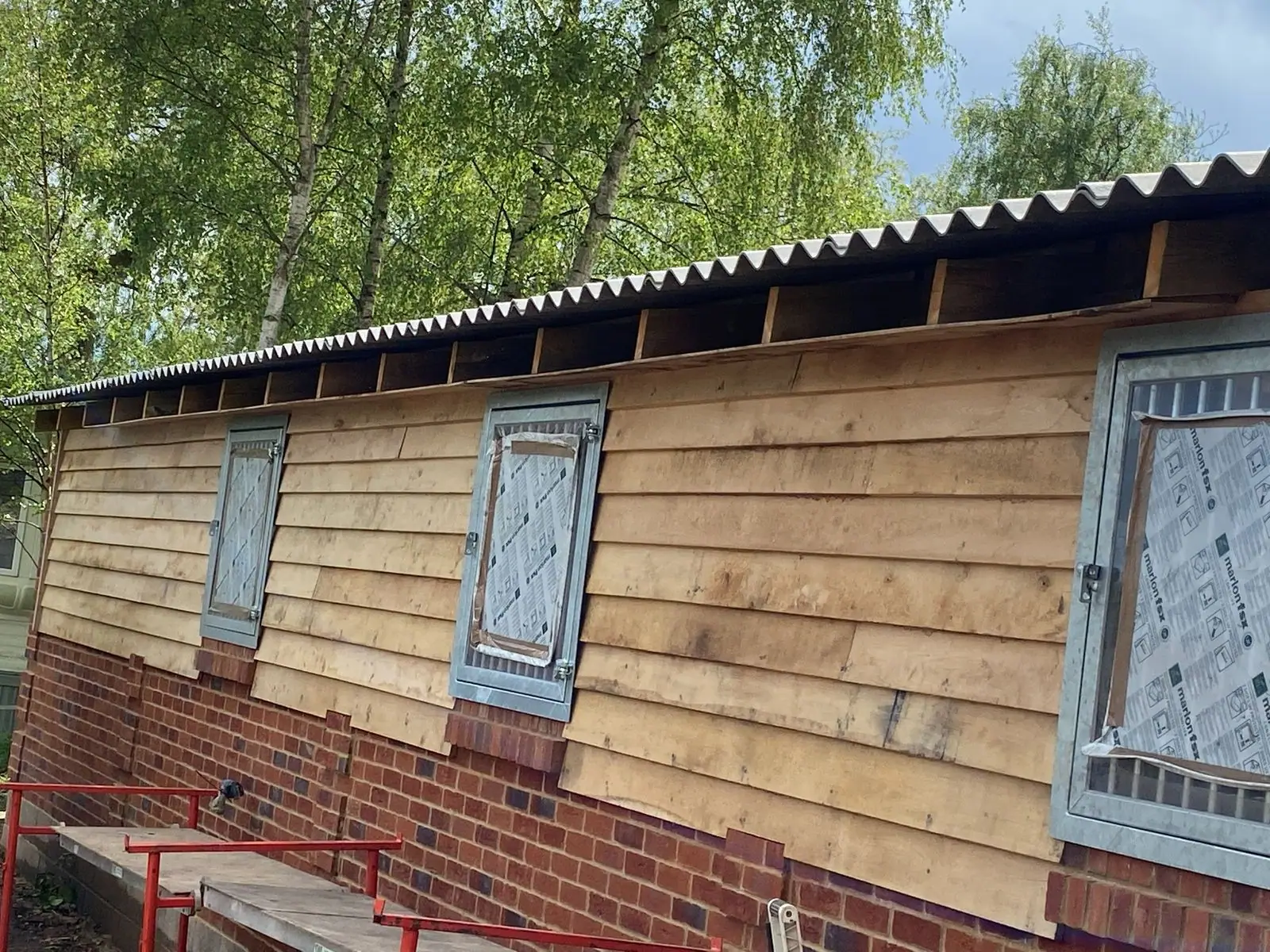 Timber-clad stable block with barred windows