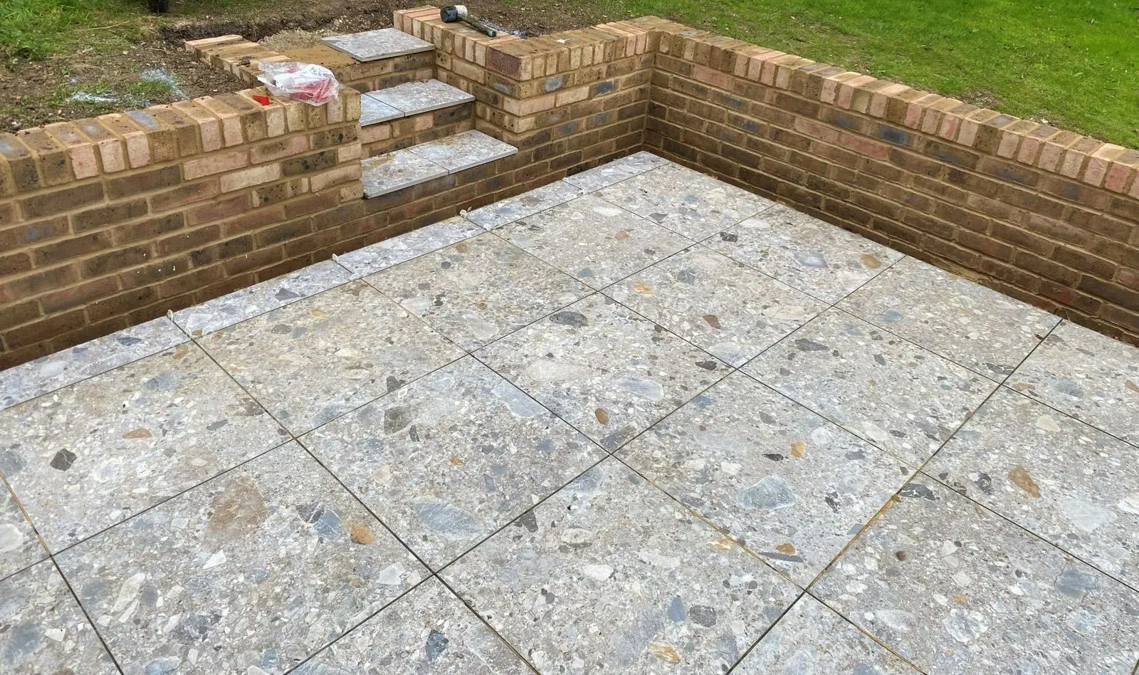 Patio with curved brick retaining walls and steps up to the lawn