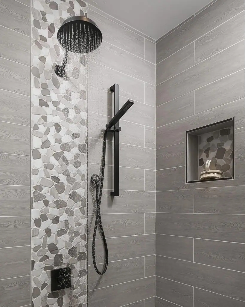 Walk-in shower with grey tiling, a pebble mosaic feature strip and a built-in niche