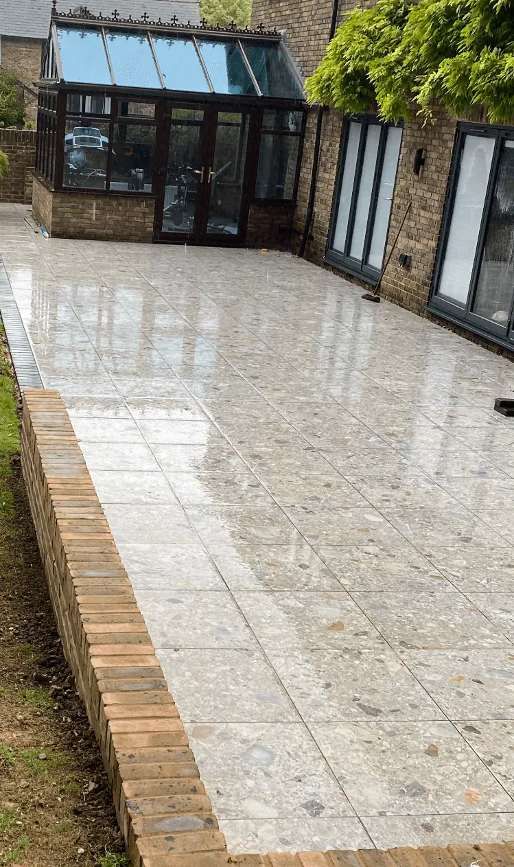 Long porcelain terrace with brick edging beside a conservatory